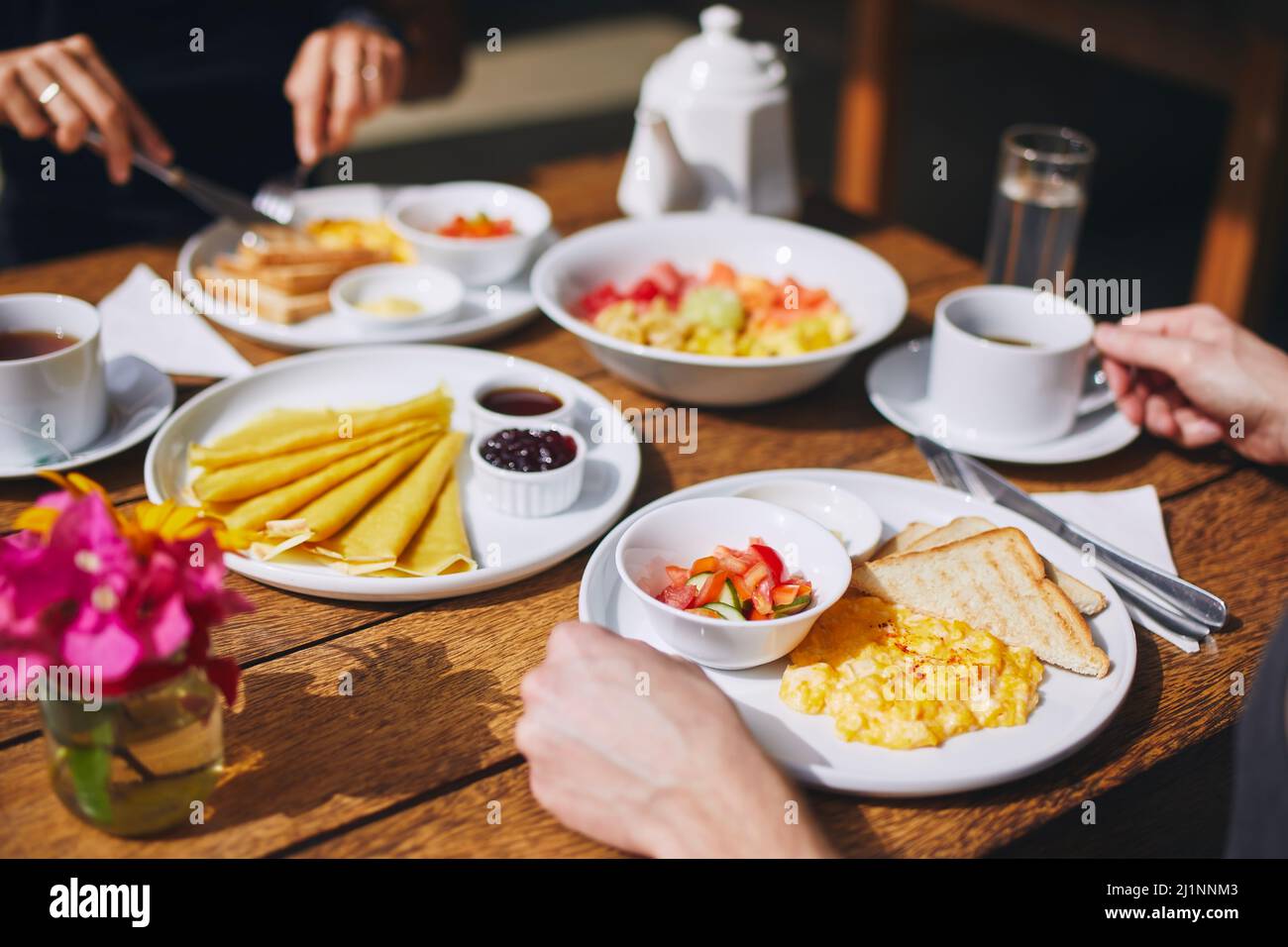 Colazione per coppia in località turistica. Uova strapazzate e pane tostato, pancake, frutta e bevande su un tavolo di legno. Foto Stock