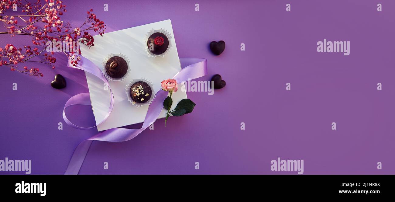 Cioccolato viola sfondo caramelle vista dall'alto con ombre e gypsofila. Striscione extra largo Foto Stock