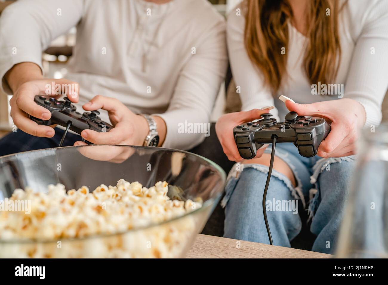 Primo piano sulle mani di sconosciuti uomo e donna che detengono il controller della console per videogiochi che giocano i videogiochi Foto Stock