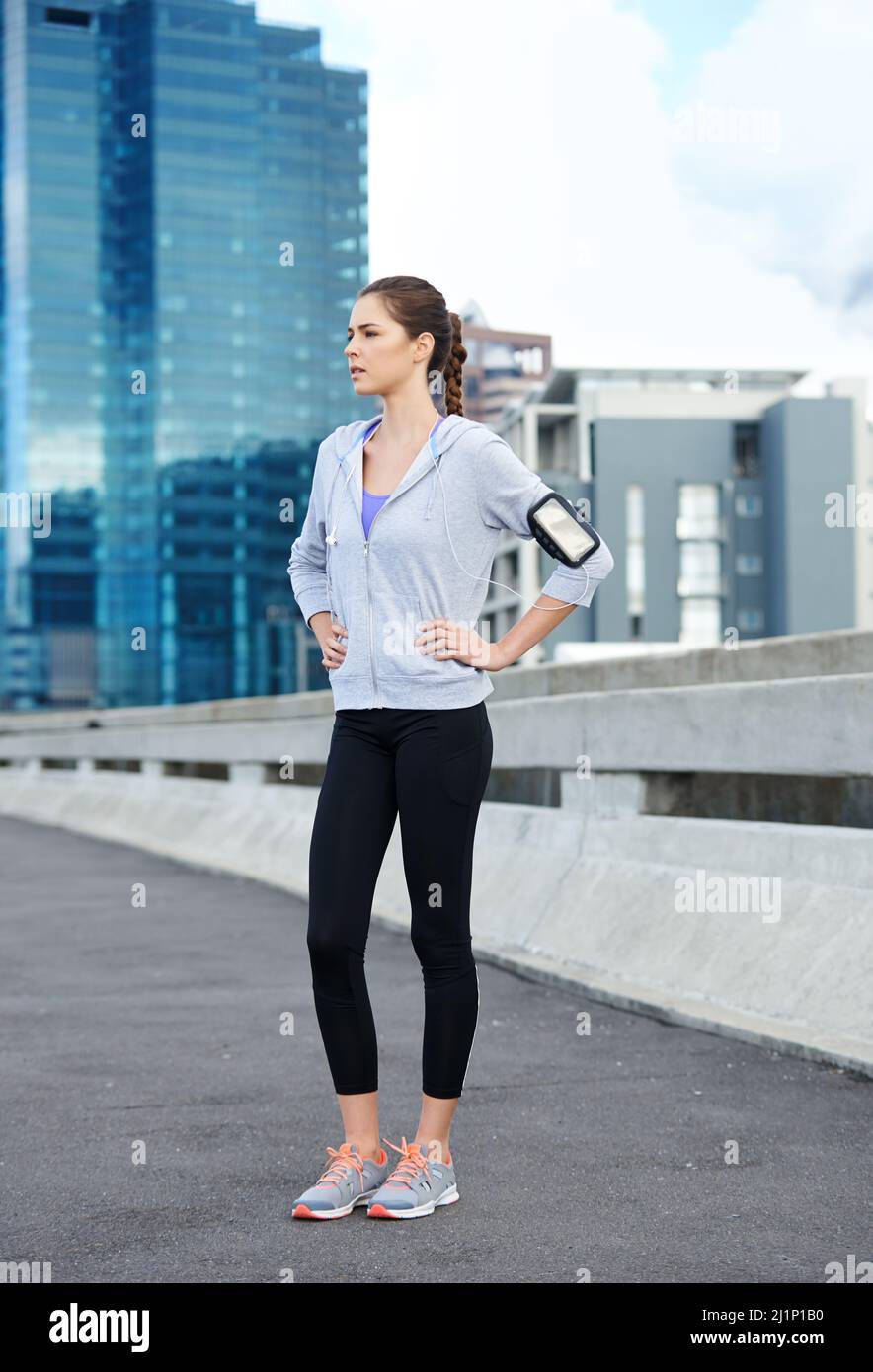 La musica mi prepara per una corsa. Scatto di una giovane jogger femminile che ascolta musica sulle cuffie prima di una corsa. Foto Stock