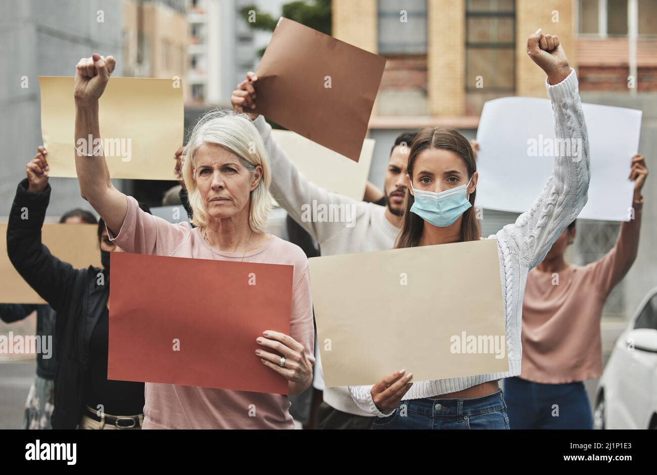 È qui che facciamo la nostra posizione. Ritratto ritagliato di un gruppo di persone che hanno dei segni durante la partecipazione a un raduno politico. Foto Stock