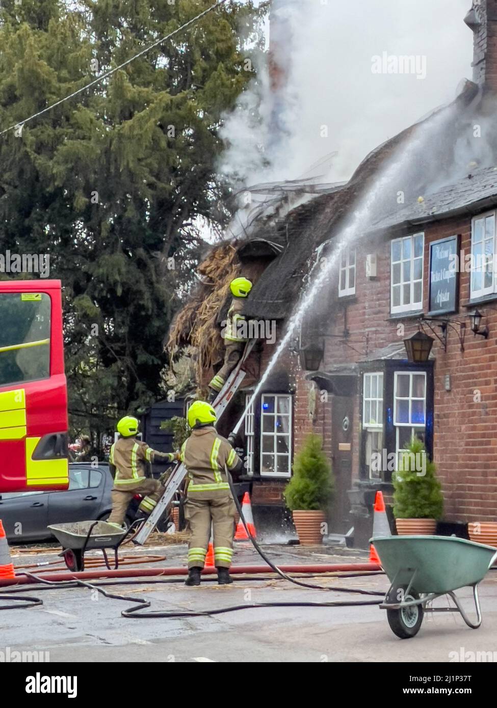 Zafferano Walden, Regno Unito. 27th Mar 2022. Fire oggi distrutto il famoso AX E BUSSOLA pub e ristorante a ARKESDEN, Saffron Walden. Essex. Il pub di paglia del 18th secolo, in essex ha preso il fuoco a mezzogiorno oggi proprio come il Christou si stava preparando per il loro giorno più trafficato dell'anno, con più di 150 prenotazioni per il pranzo del giorno delle madri. Essex vigili del fuoco e ambulanza hanno partecipato. Non sono state segnalate perdite. Molti ospiti abituali del pub all'epoca hanno aiutato a evacuare il personale e i mobili dai locali utilizzando una flotta di carriole. Credit: Mark Bourdillon/Alamy Live News Foto Stock