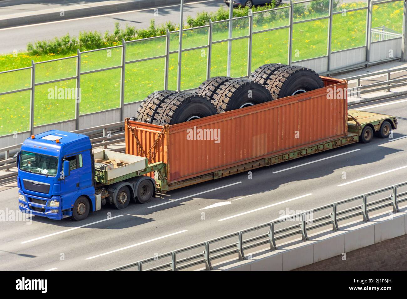 Trasporto di enormi ruote di autocarro di scarico in un container su un rimorchio. Foto Stock