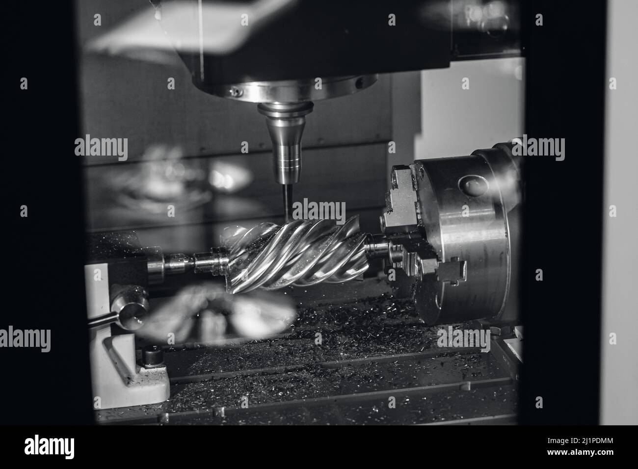 La fresatrice CNC industriale lavora la parte di vite senza fine in acciaio con trucioli metallici. Foto Stock