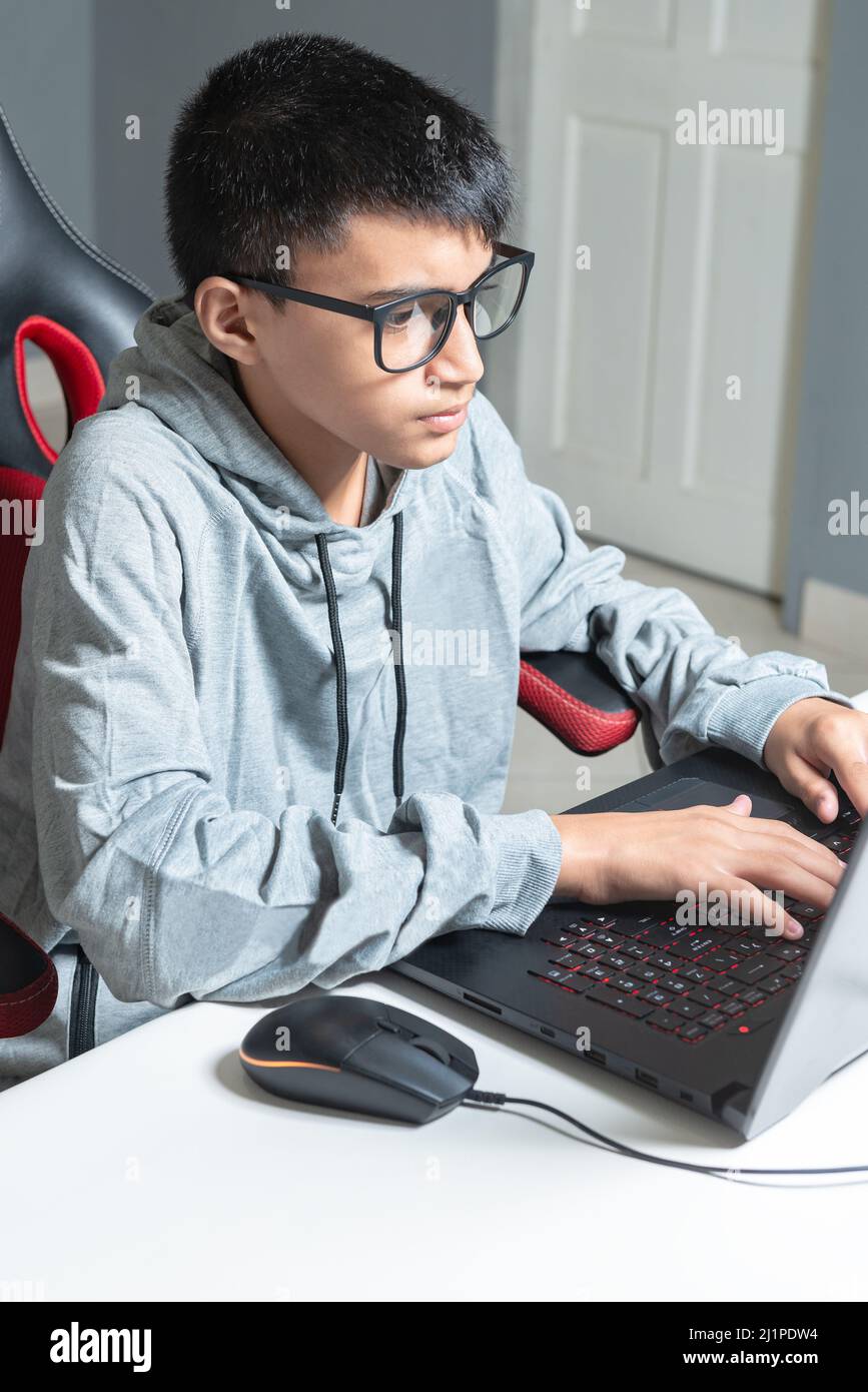 Teen adolager ragazzo casa scuola studiare stanza scrivania pc computer vetri seduta guardando i compiti Foto Stock