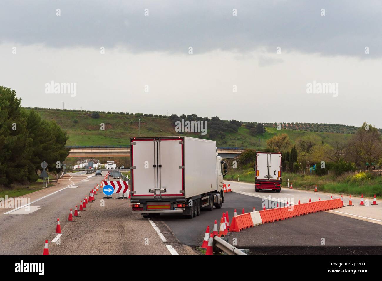 Carrelli refrigerati che cambiano corsia su un'autostrada chiusa per lavori. Foto Stock