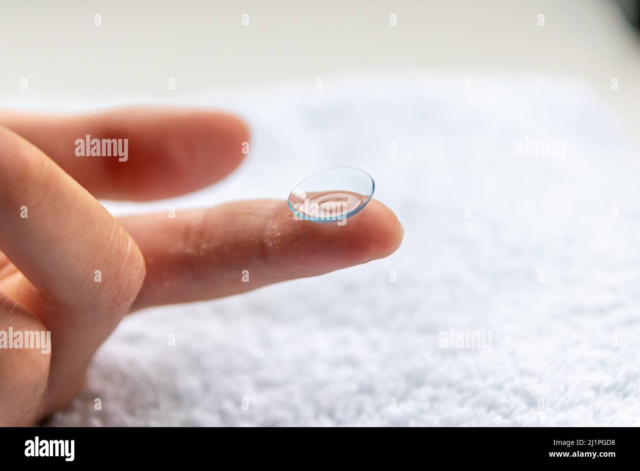 La pulizia della lente di contatto sul dito per correggere la miopia e la vista offuscata da ottico o oculista è da maneggiare con igiene per correggere Foto Stock
