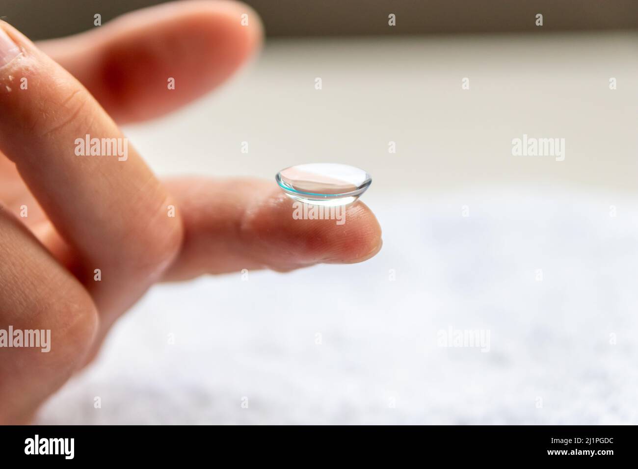 La pulizia della lente di contatto sul dito per correggere la miopia e la vista offuscata da ottico o oculista è da maneggiare con igiene per correggere Foto Stock