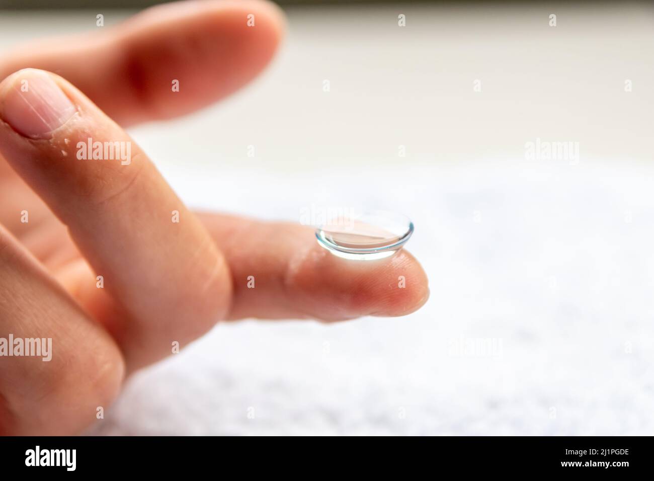 La pulizia della lente di contatto sul dito per correggere la miopia e la vista offuscata da ottico o oculista è da maneggiare con igiene per correggere Foto Stock