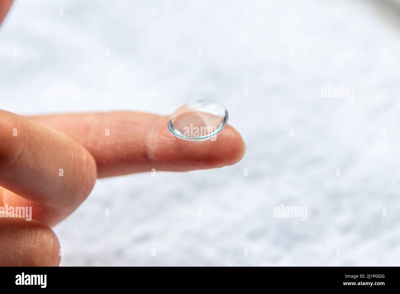 La pulizia della lente di contatto sul dito per correggere la miopia e la vista offuscata da ottico o oculista è da maneggiare con igiene per correggere Foto Stock