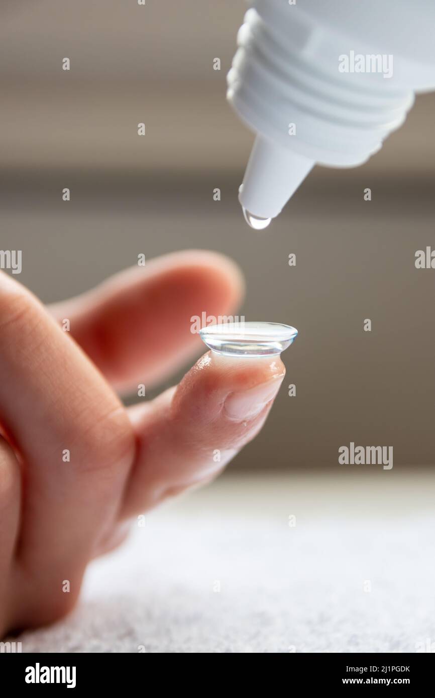 La pulizia della lente di contatto sul dito per correggere la miopia e la vista offuscata da ottico o oculista è da maneggiare con igiene per correggere Foto Stock