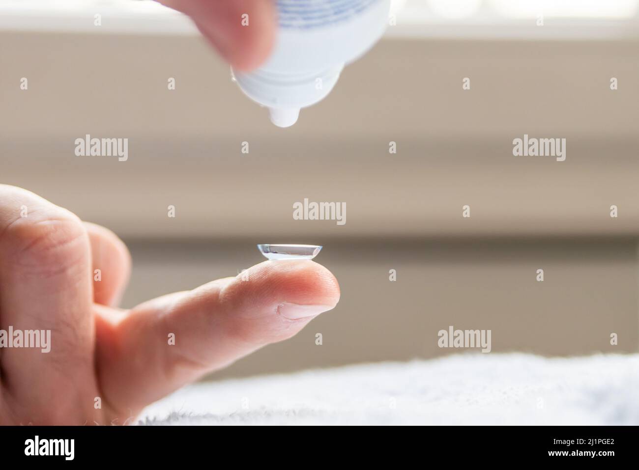 La pulizia della lente di contatto sul dito per correggere la miopia e la vista offuscata da ottico o oculista è da maneggiare con igiene per correggere Foto Stock