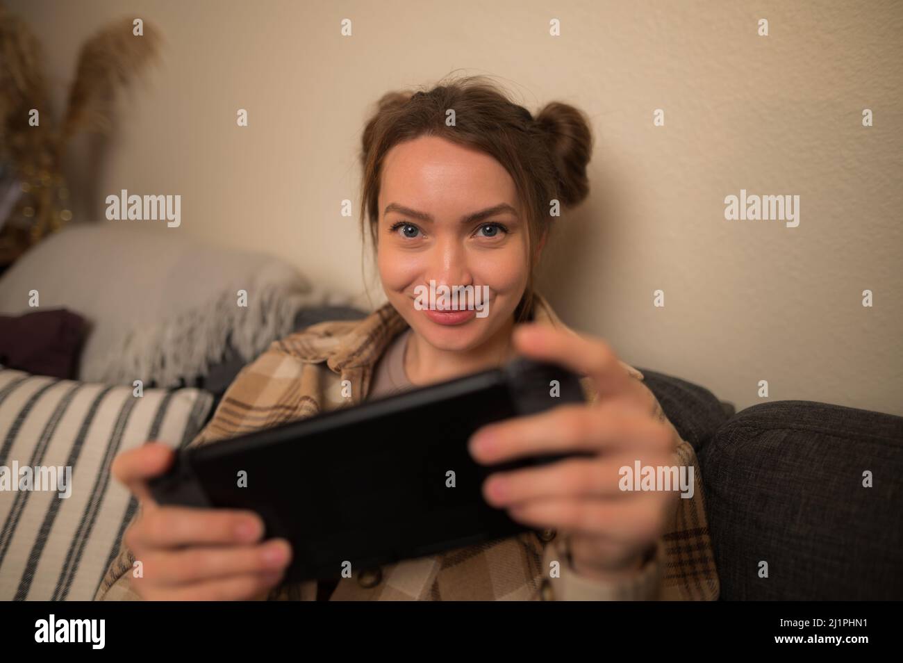 Ragazza gamer guarda lo schermo di una console di gioco portatile. Videogiochi, giochi mobili, intrattenimento, tempo libero, premi, vittorie, strategia di gioco. Cultura giovanile Foto Stock