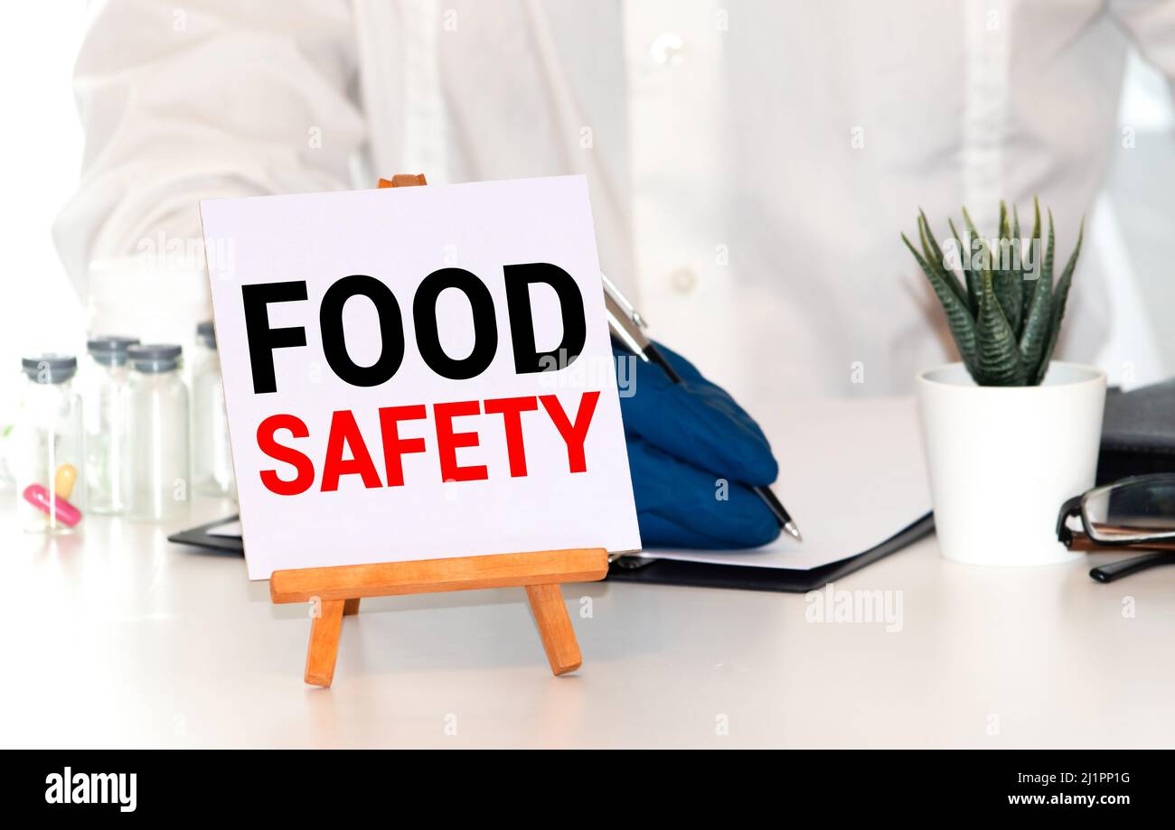 Medico che tiene una scheda con il testo sicurezza alimentare, concetto medico. Foto Stock