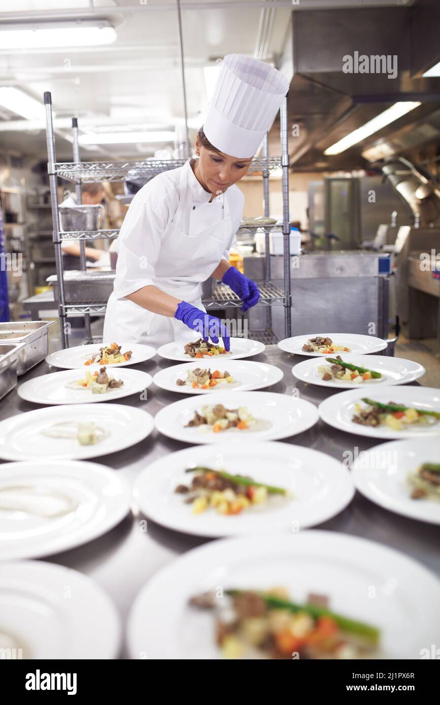 Mani capaci in cucina. Shot di uno chef piatto cibo per un servizio pasti in una cucina professionale. Foto Stock
