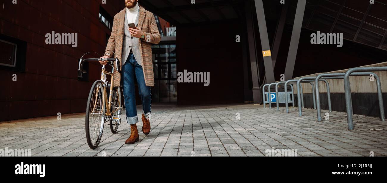 Copertina photo.Hipster camminare con la bicicletta e utilizzando uno smartphone.andare dal lavoro. Foto Stock