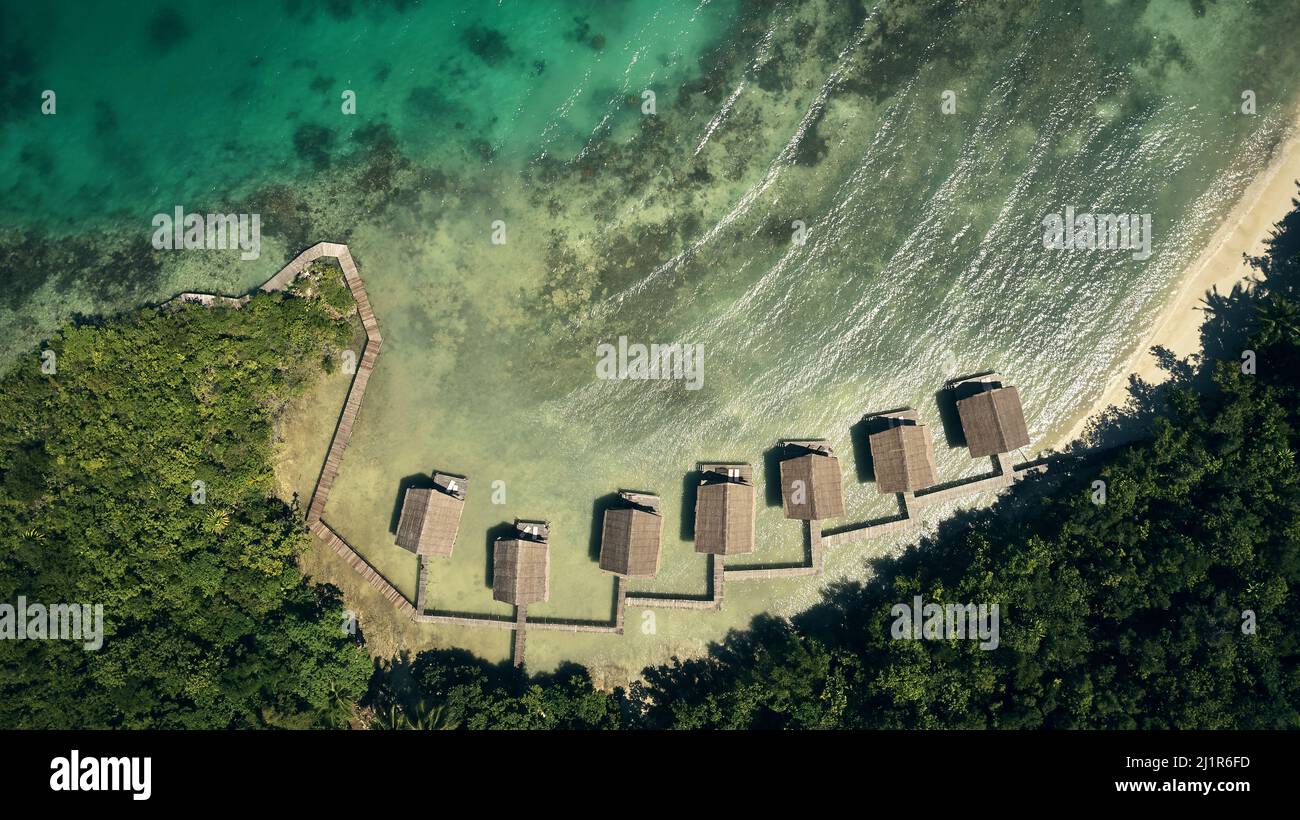 La tua esperienza irripetibile ti aspetta. Alto angolo di bungalow lungo le coste dell'isola di Indonesia. Foto Stock