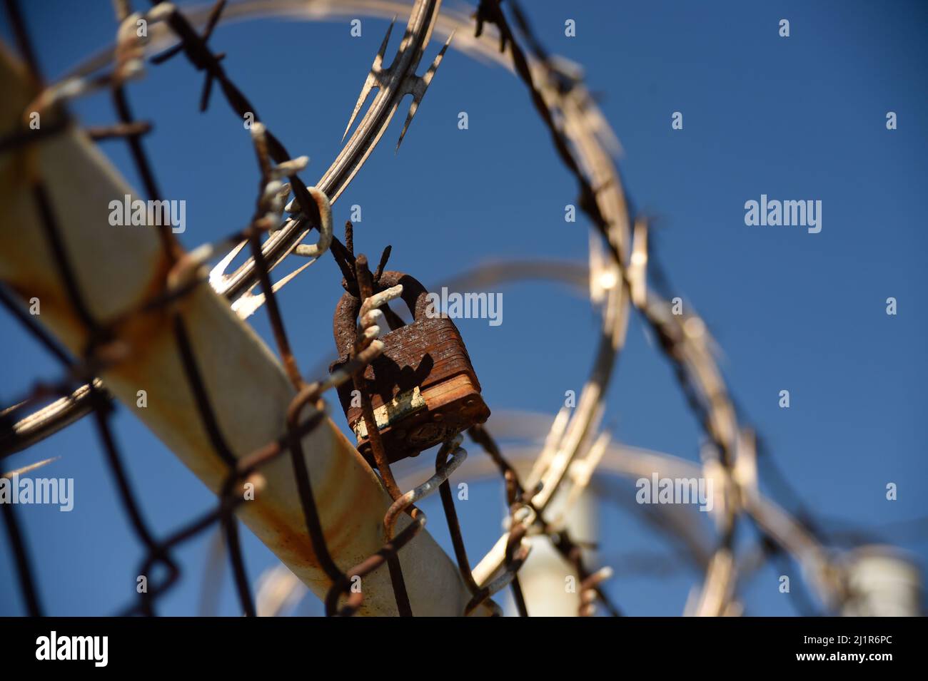 Lucchetto arrugginito fissato al filo spinato a San Diego, California Foto Stock