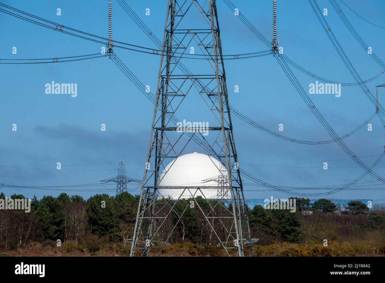 La cupola bianca della centrale nucleare di Sizewell vista attraverso la struttura metallica di un pilone Foto Stock