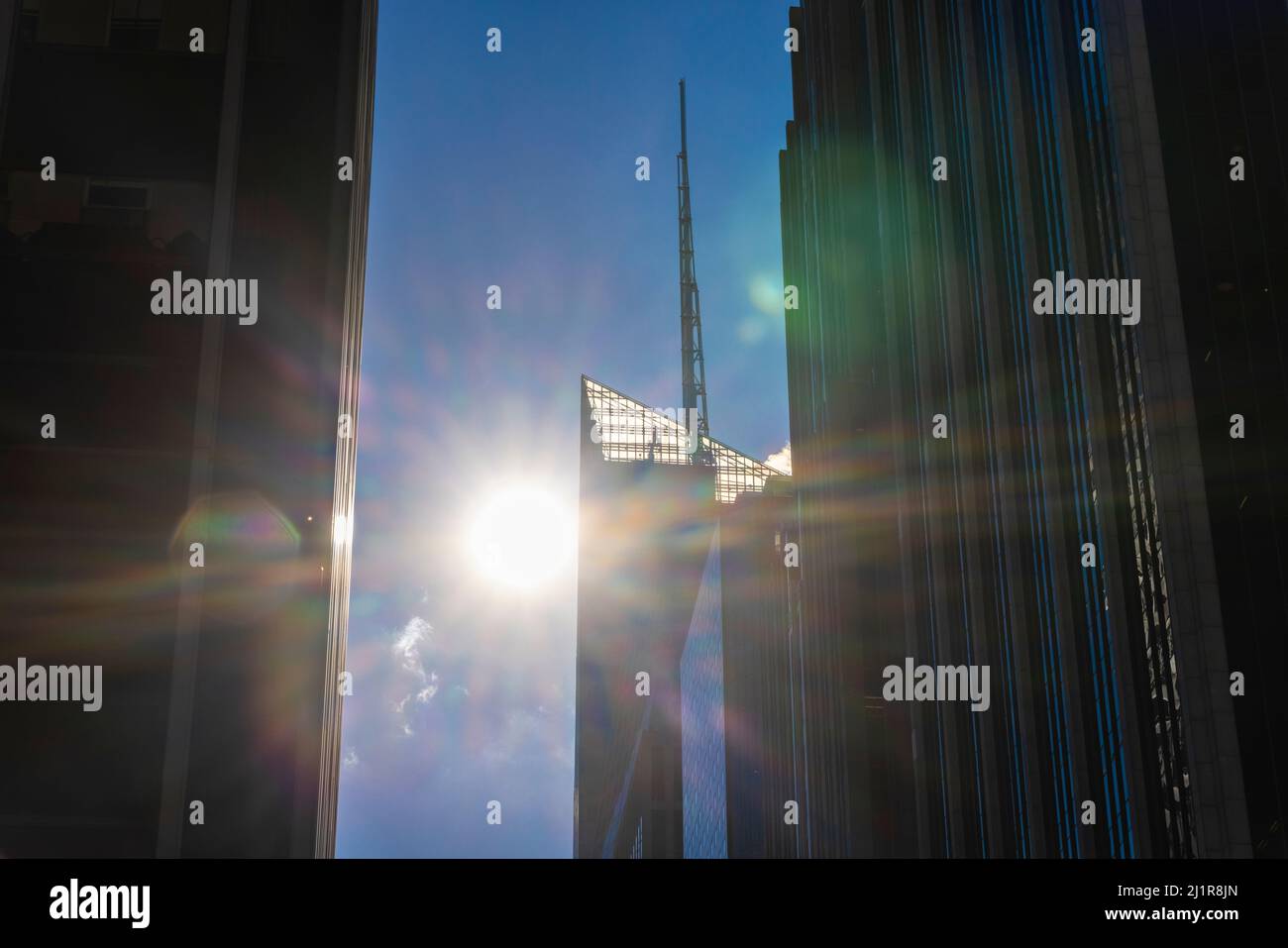 Il sole splende tra file di alti edifici nel centro di Manhattan NYC. Foto Stock