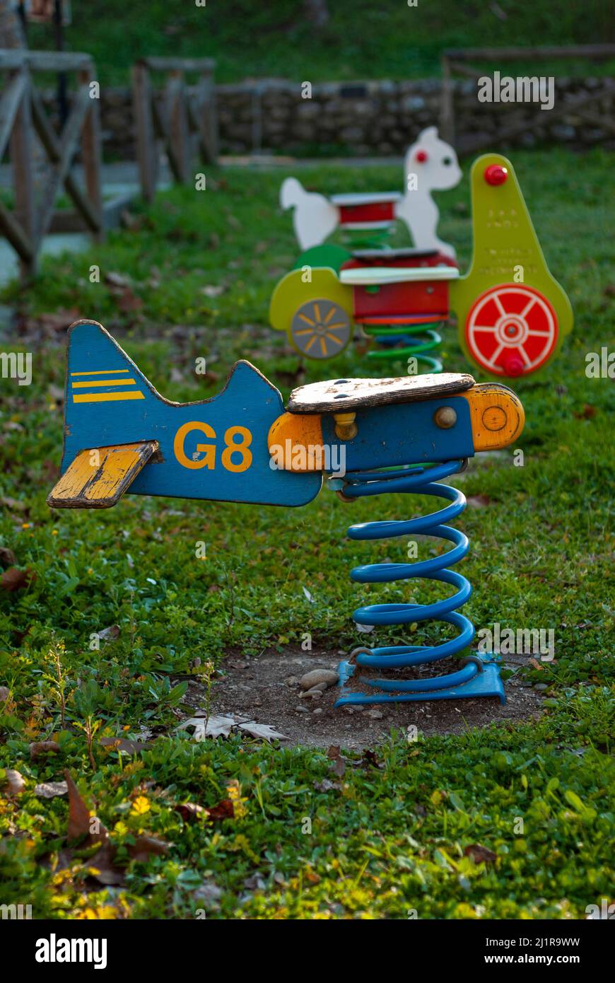 L'altalena a forma di un aereo di legno con una molla in un parco giochi per bambini è al tramonto in verticale Foto Stock