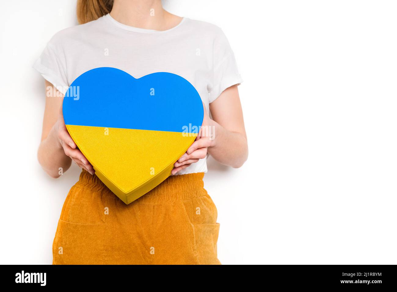 Donna che tiene una grande scatola gialla e blu a forma di cuore. Banner alla moda a colori della bandiera Ucraina Foto Stock