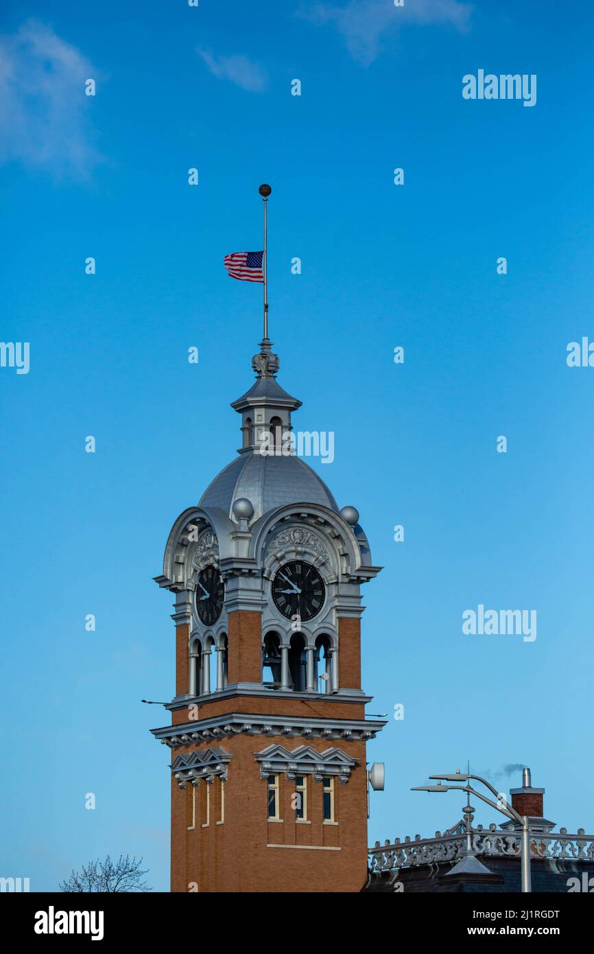 Bandiera che vola a metà del personale in cima alla torre dell'orologio che si trova in cima al circuito di tribunale della contea di lincoln a merrill, Wisconsin Foto Stock