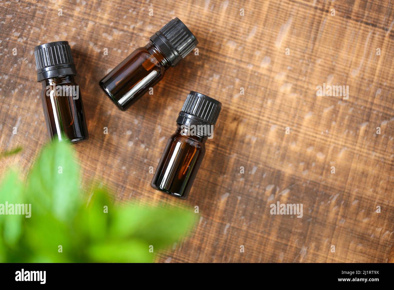 Olio essenziale di menta piperita.bottiglia di vetro e menta piperita fresca su sfondo di legno.Aromatherapy e cosmetici naturali biologici. Foto Stock