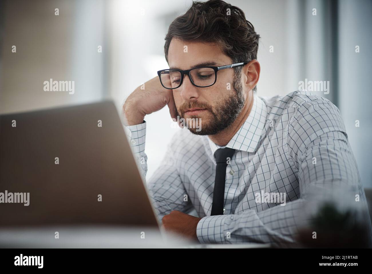 Forse il suo tempo per un cambiamento di carriera. Scatto di un giovane uomo d'affari che guarda annoiato mentre lavora in un ufficio. Foto Stock