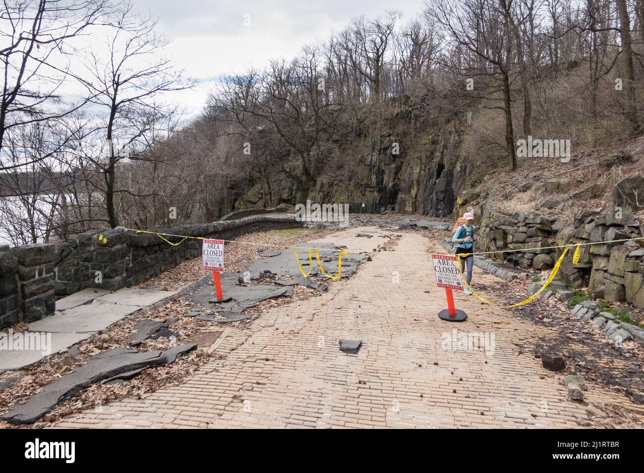 Giovane donna asiatica, vestito sportivo colorato, corsa / esercizio lungo la tempesta ha danneggiato strada nel Palisades, New Jersey Foto Stock