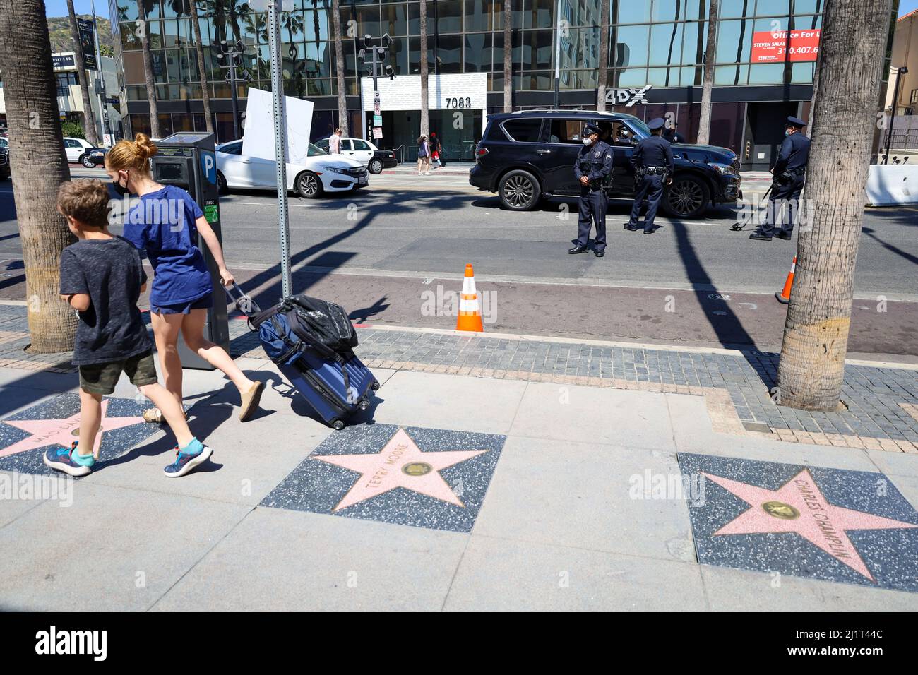 Hollywood, California, Stati Uniti. 30th Mar 2022. Due bambini si muovono lungo la Hollywood Walk of Fame mentre la polizia controlla le auto per le bombe che entrano nella zona per i partecipanti al premio Academy, proprio prima degli eventi Red Carpet il 27 marzo 2022. Il traffico è molto controllato per motivi di sicurezza. (Credit Image: © Amy Katz/ZUMA Press Wire) Foto Stock