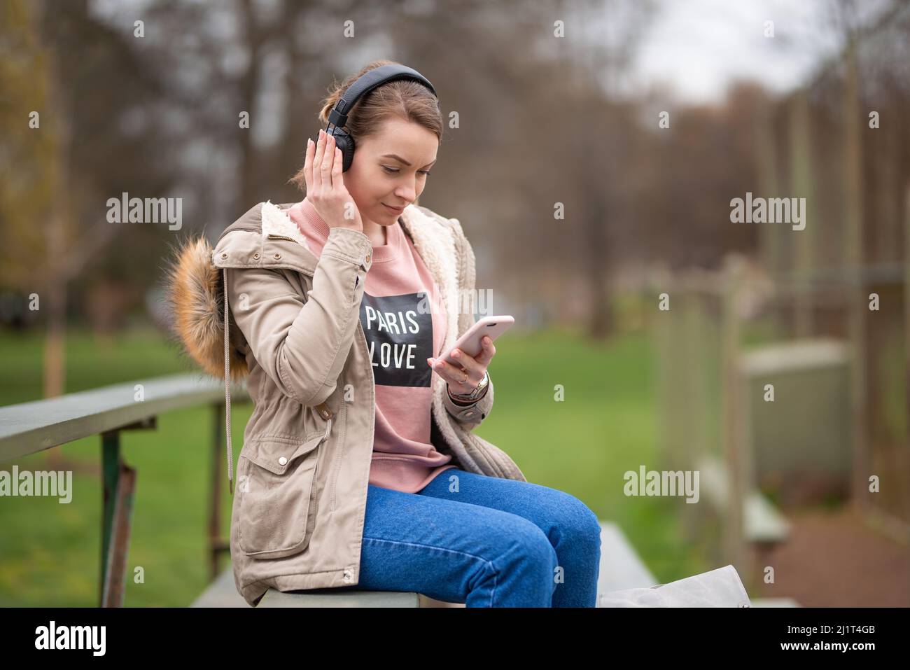 ragazza allegra ed energica, in una passeggiata nel parco con cuffie e un telefono, ascolta musica, con spazio vuoto, una passeggiata e riposo all'aria aperta, r Foto Stock