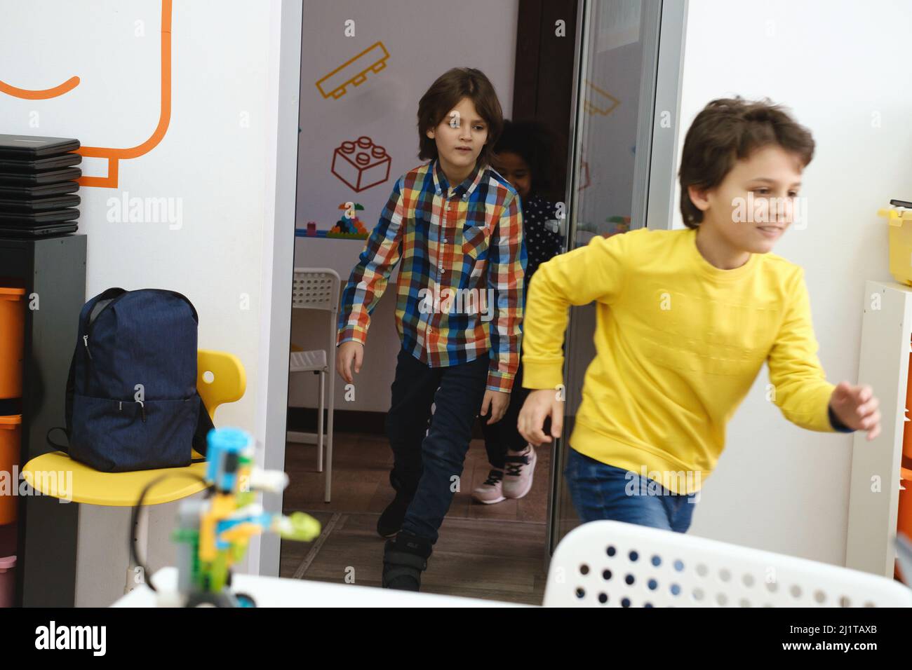 Bambini alunni che corrono nella stanza della scuola sul freno. I bambini felici che si divertono a scuola elementare. Istruzione moderna Foto Stock