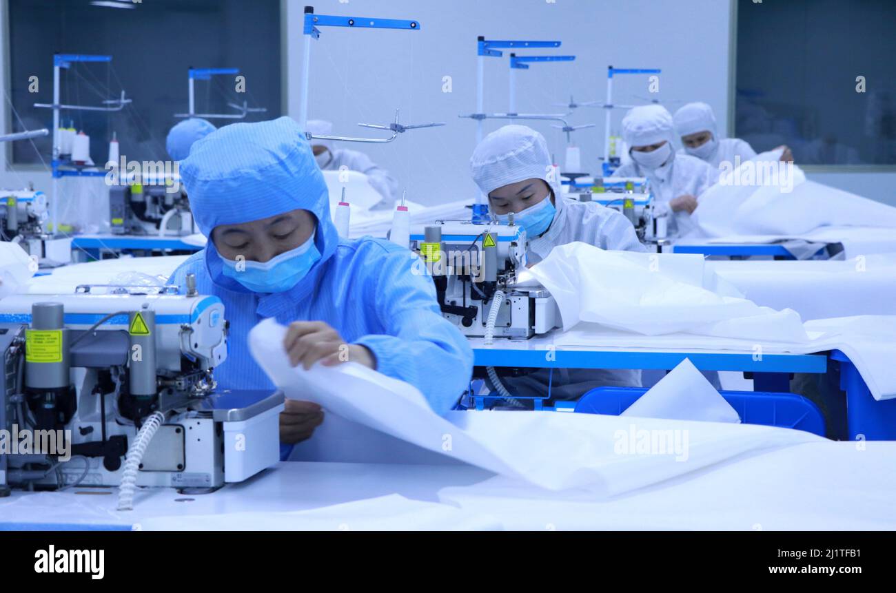 BINZHOU, CINA - 27 MARZO 2022 - i lavoratori producono materiali di prevenzione epidemica come maschere e tute protettive in un laboratorio di prodotti medici Foto Stock