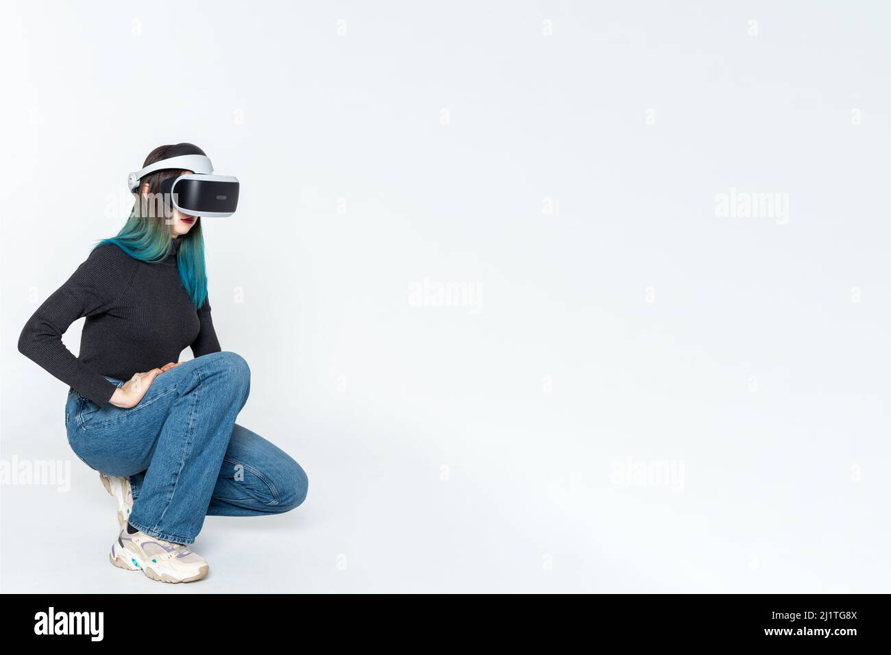 Una ragazza adolescente in un casco vr gioca nell'universo virtuale isolato su uno sfondo bianco, spazio copia. Il concetto dell'universo virtuale. Lifestyl Foto Stock