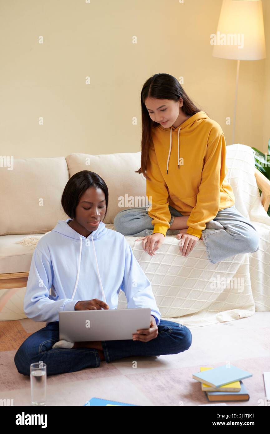 Seria giovane donna nera che mostra il suo codice di programmazione sullo schermo del laptop ad un amico e che chiede consigli Foto Stock
