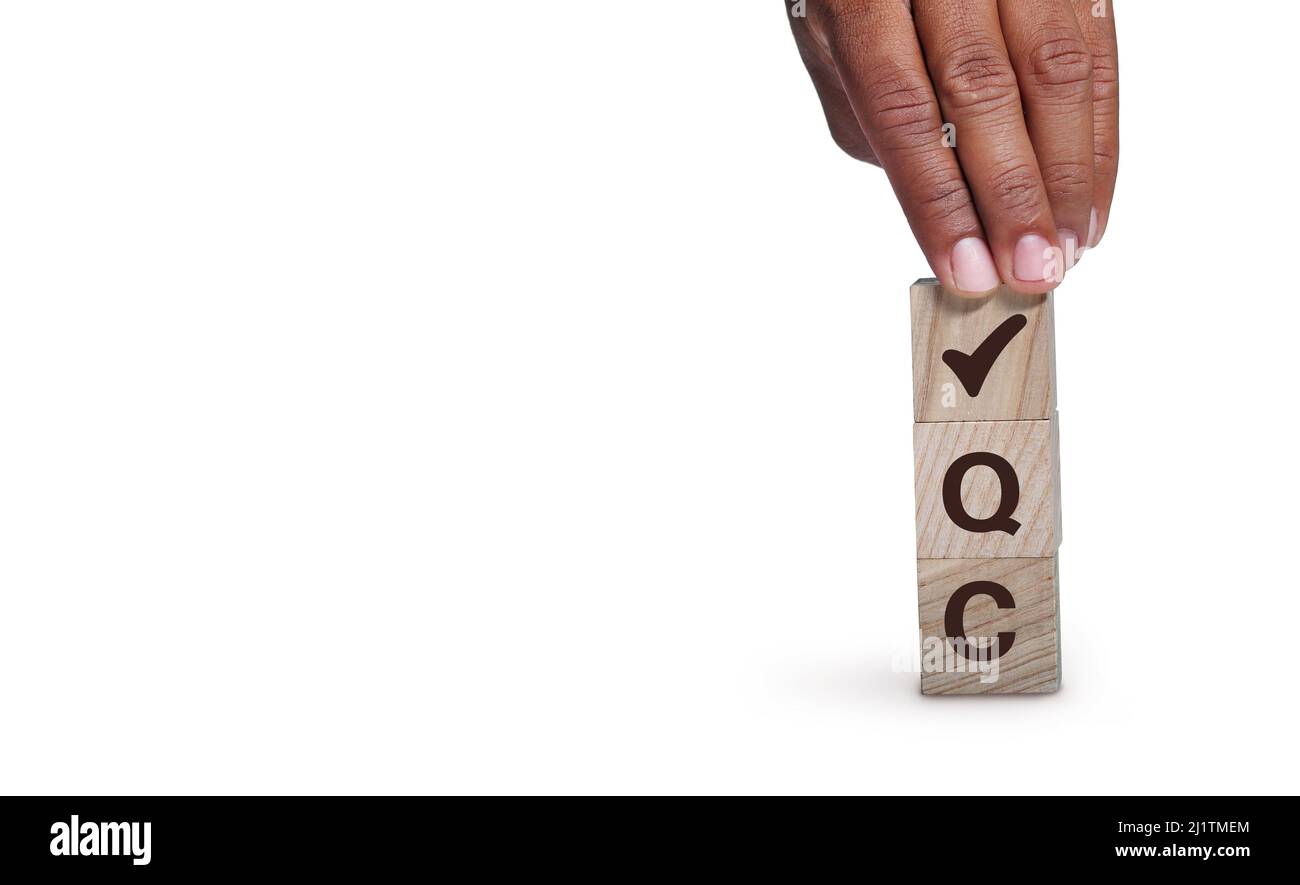 Concetto di controllo di qualità (QC). Per affari. Qualità standard, garanzia, processo, controllo e approvazione. La mano tiene i cubetti di legno con l'assegno Foto Stock