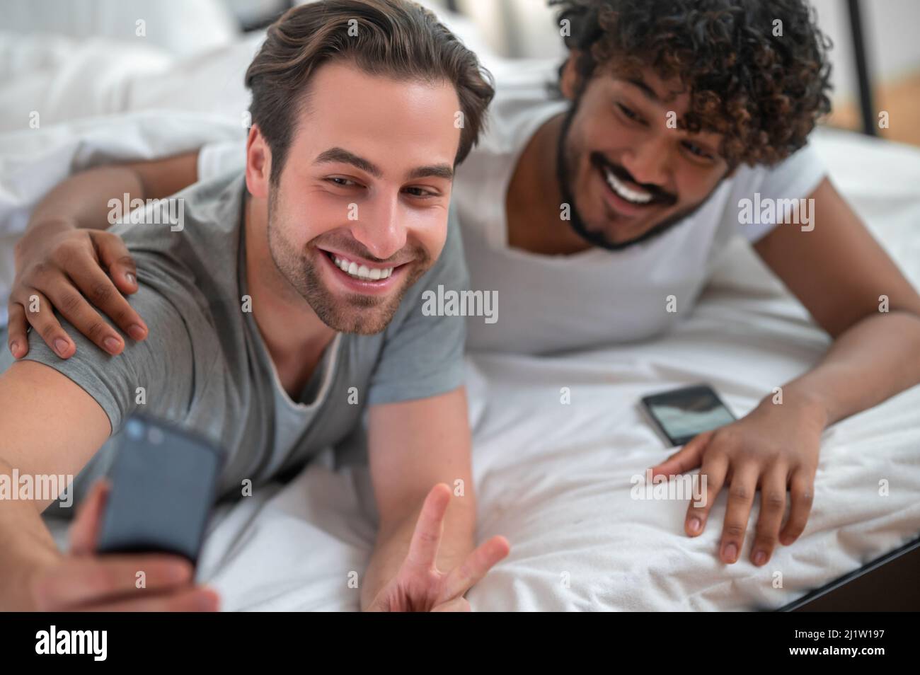 Allegro giovane coppia biraciale gay prendendo selfie Foto Stock