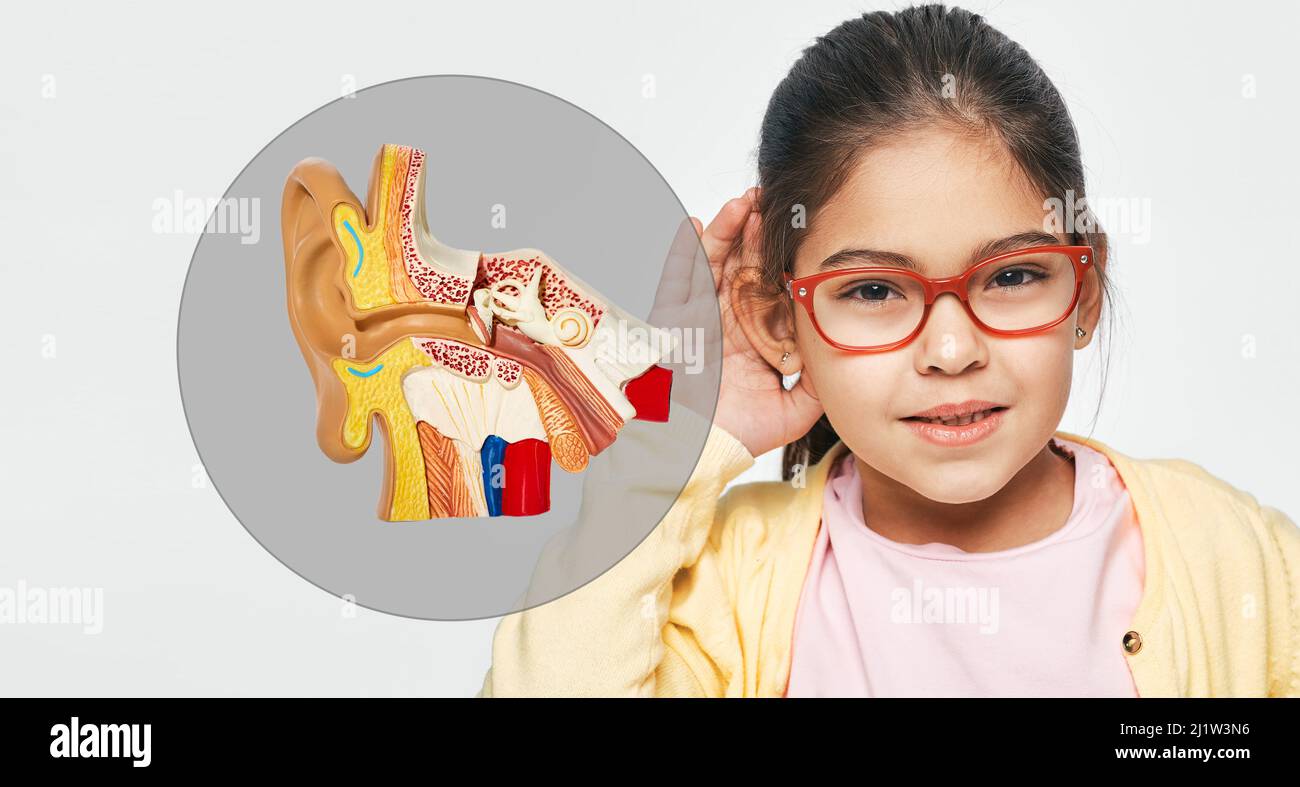 Problemi di udito nei bambini e trattamento della sordità. La bambina tiene la mano vicino all'orecchio per ascoltare il suono Foto Stock