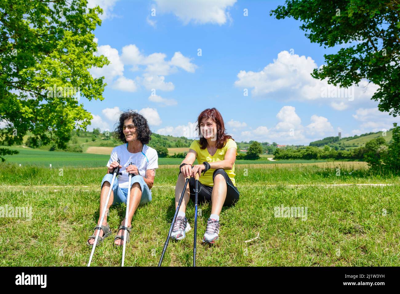 Due donne sportive che fanno una pausa durante un'esercitazione nordic walking vicino un piccolo stagno Foto Stock