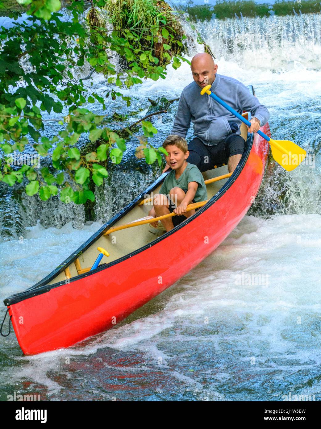 Padre e figlio si addicchiano in canoa uno stramazzo Foto Stock