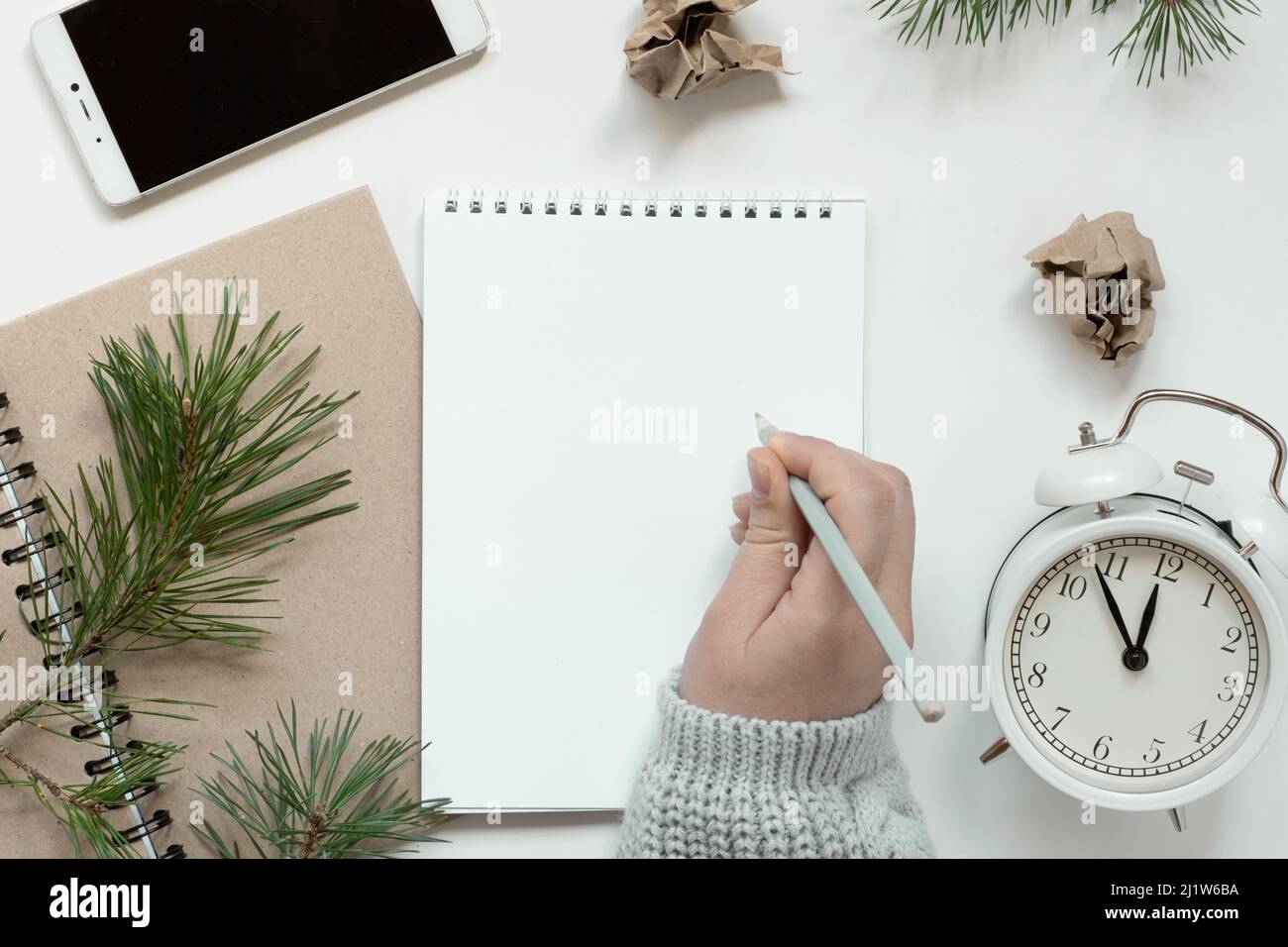 La mano della donna che scrive in taccuino vuoto. Risoluzioni, piano, obiettivi, lista di controllo, concetto di idea. Disposizione piatta, spazio di copia. Natale, Capodanno. Pagina bianca Foto Stock