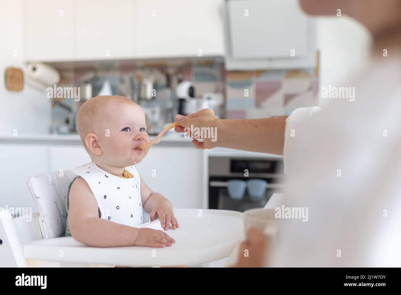 la prima alimentazione del bambino, la mamma nutre un bambino con un cucchiaio Foto Stock