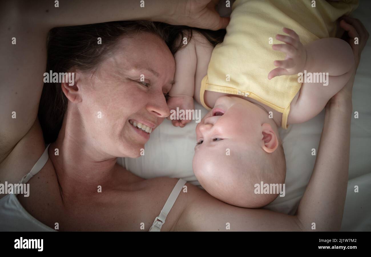madre e bambino ridendo e sdraiati sul letto vista dall'alto, concetto di maternità, giorno della madre Foto Stock
