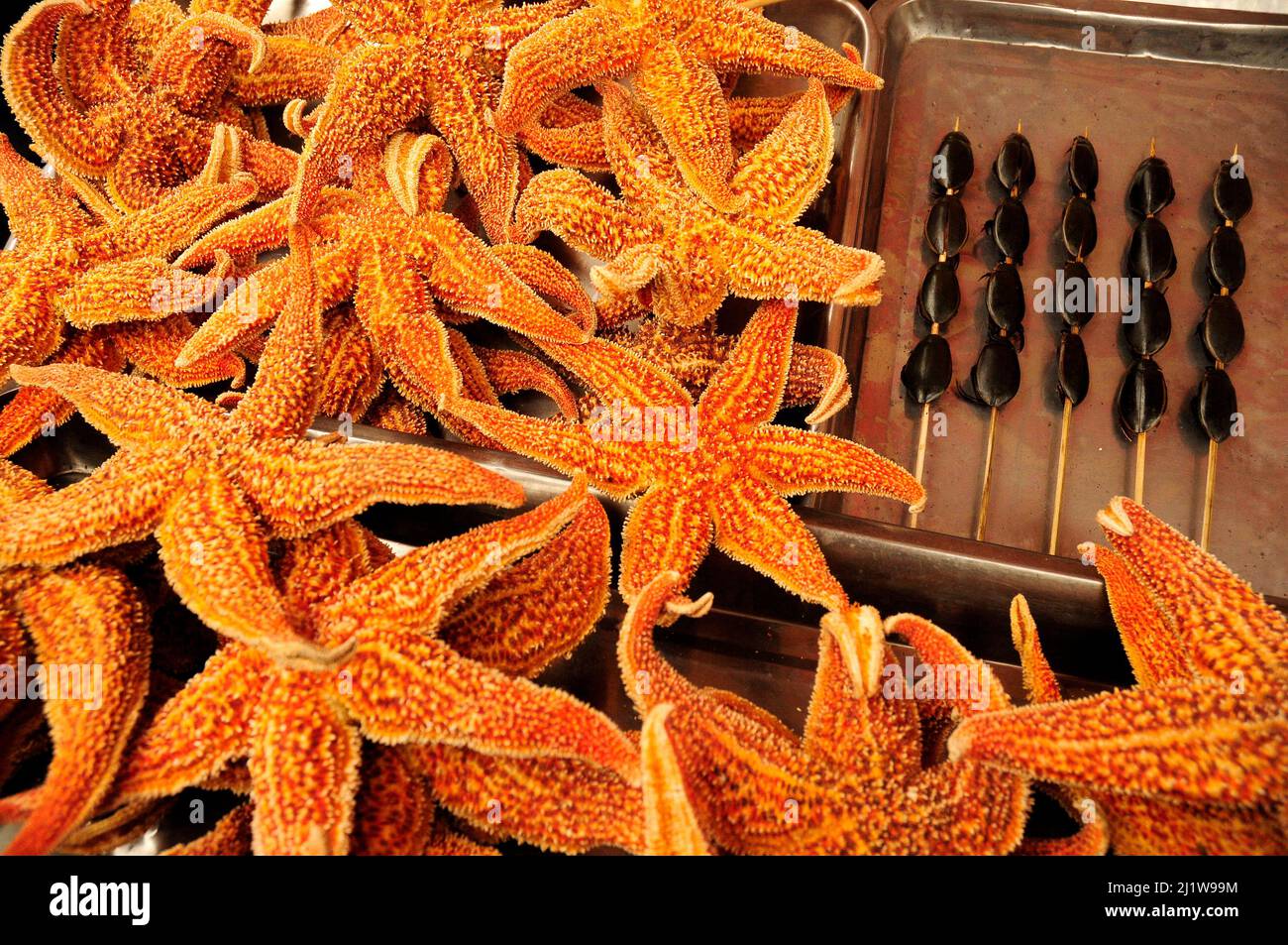 Stelle marine accanto agli scarabei acquatici sugli spiedini. Mercato alimentare all'aperto nel centro di Pechino, Cina. Foto Stock