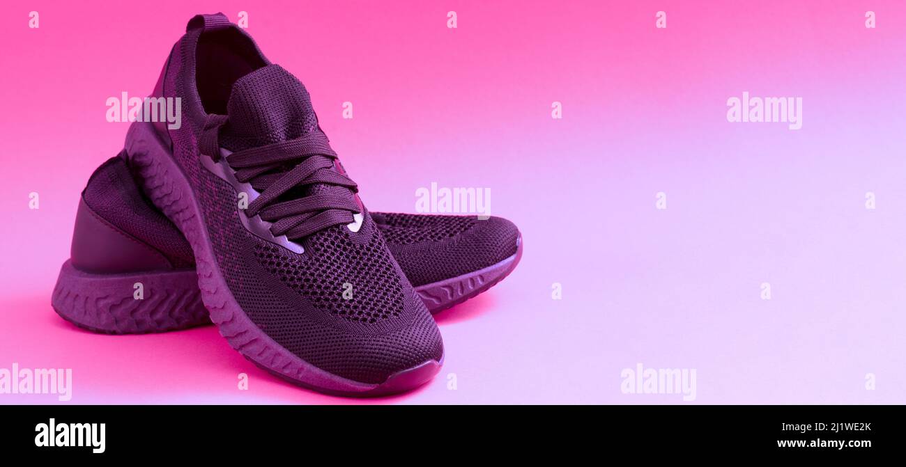 Design sneakers con spazio per il testo. Primo piano di sneaker rosa su sfondo luminoso. Scarpe sportive per la corsa e il fitness. Paio di scarpe. Stile di vita attivo. Texture con suola viola e lacci. Foto Stock