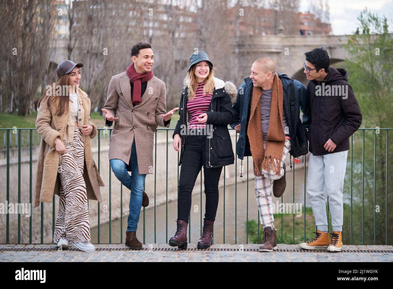 Gruppo di amici di diverse età ed etnie parlano e ridono all'aperto. Foto Stock