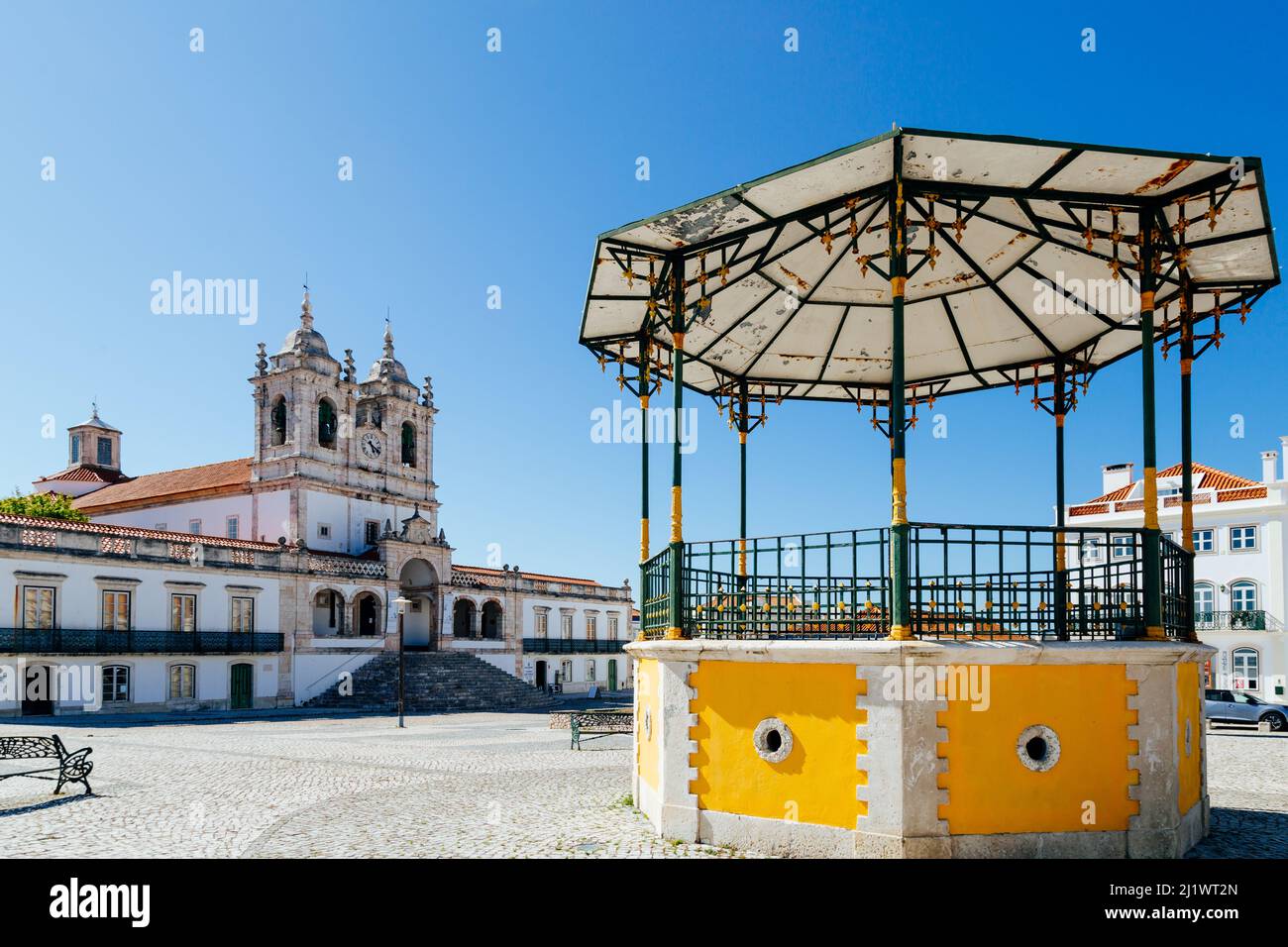 Piazza della città vecchia di Nazaré con palco giallo e la chiesa di Nossa senhora da Nazaré sullo sfondo in una giornata estiva di sole Foto Stock