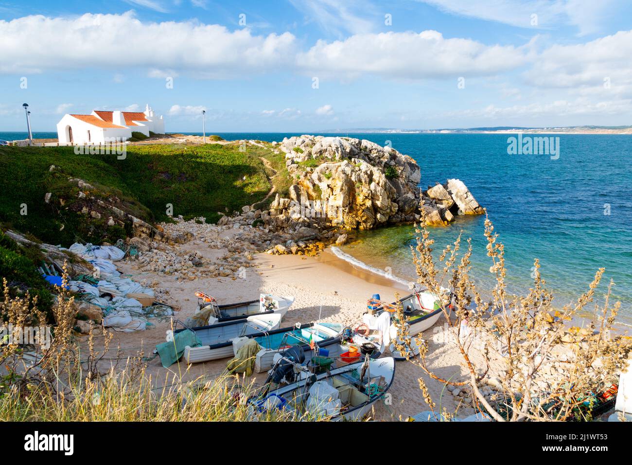 Bella insenatura di pescatori con le barche da pesca sulla sabbia e Saint Stephen Hermitage a Peniche Foto Stock