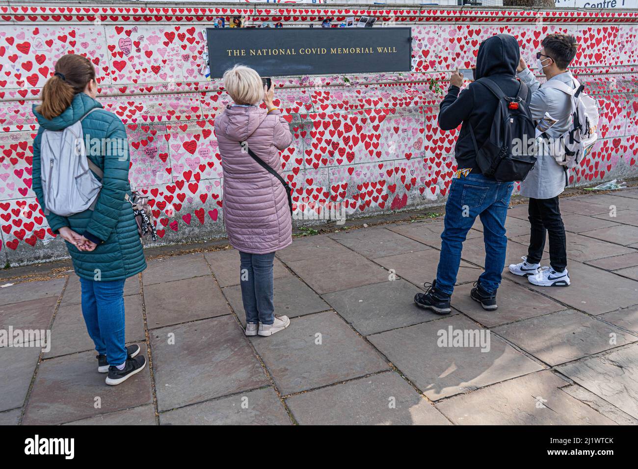 LONDRA, REGNO UNITO. 28 marzo 2022. I membri del pubblico considerano i cuori dipinti al muro commemorativo nazionale per ricordare le vittime della pandemia del coronavirus. Si è verificato un aumento del numero di casi secondo i dati dell'Ufficio per le statistiche nazionali in Inghilterra causato dalla variante Omicron BA.2 un virus ricombinante che contiene elementi delle varianti Delta e Omicron, in quanto il numero di infezioni COVID-19 è salito a 4,26 milioni nei sette Giorni al 19 marzo - aumento del 29,7% sulla settimana prima. Credit: amer Ghazzal/Alamy Live News Foto Stock